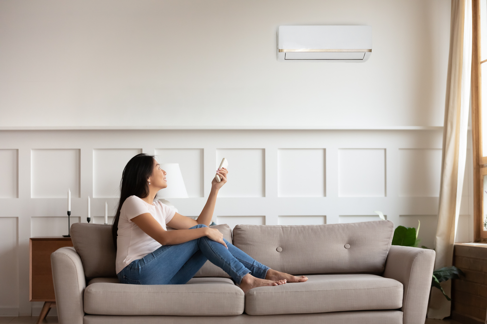 woman sitting on couch turning on ductless ac system
